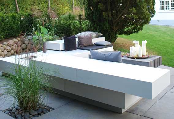 Hvidt loungemøbel på oval terrasse med natursten designet af havearkitekt Tor Haddeland