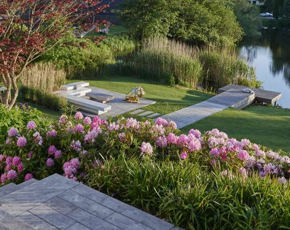 Kig til sø og terrasse med Haddeland Lounge designet af havearkitekt Tor Haddeland